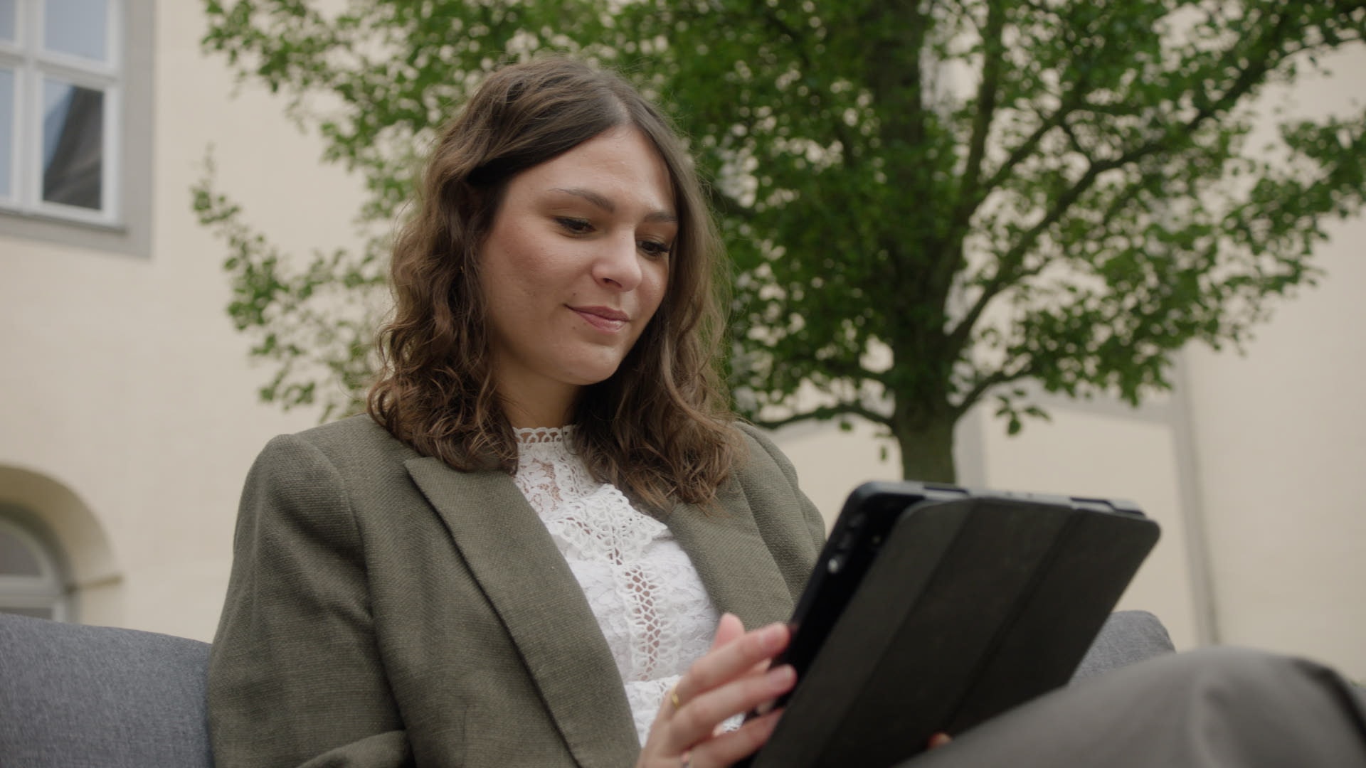 Selbstständige Traurednerin Vera arbeitet im Freien an ihrem Tablet und bereitet eine Trauung vor.