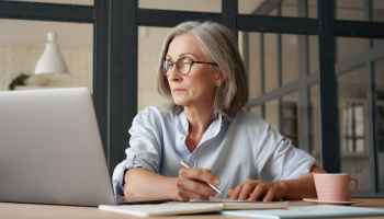 Frau an Laptop macht sich Notizen zur DSGVO für ihren Onlineshop